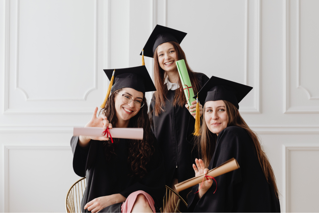 invitacion-digital-boda-celebration-light-tres-estudiantes-mujeres-con-toga-y-birrete-sosteniendo-diploma-fondo-blanco