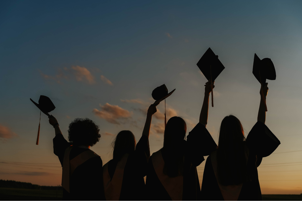 invitacion-digital-gradua-celebration-light-fotografia-horizontal-estudiantes-con-toga-levantando-birrete-frente-atardecer
