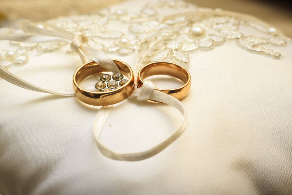 invitacion-digital-boda-golden-blue-foto-argollas-doradas-con-lazo-blanco-sobre-fondo-cojin