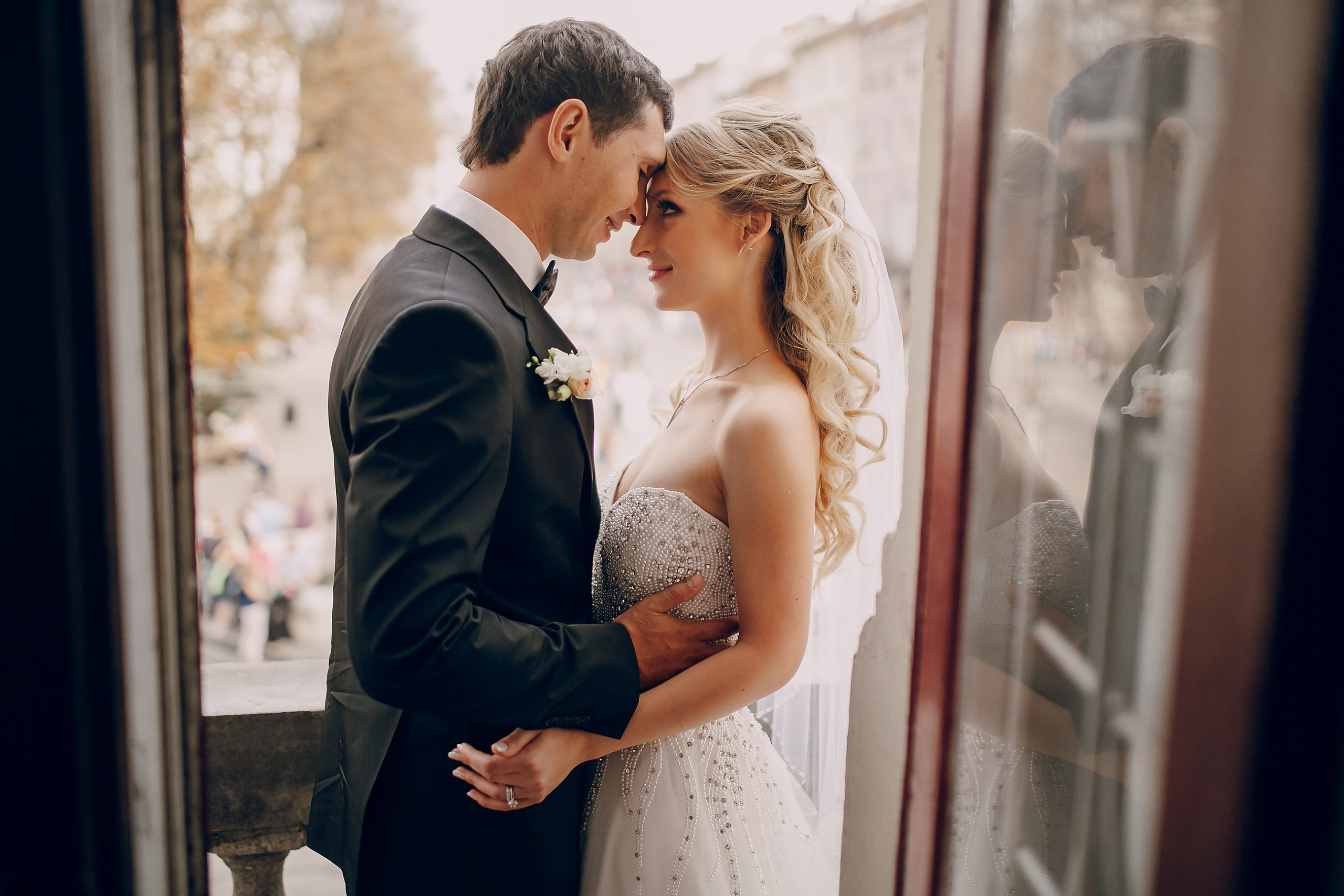 in-boda-classic-fotografia-pareja-de-pie-y-de-frente-en-balcon-ventana-vestido-blanco-traje-negro.jpg